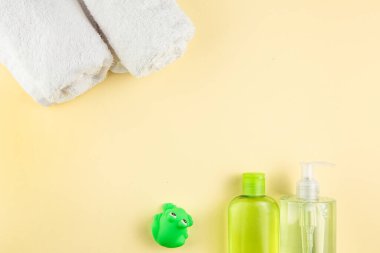 Spa ve banyo konsepti. Bebek banyosu. Lastik ördek, bez, sabun şişesi, şampuan, havlu ve sarı arka planda tarak..
