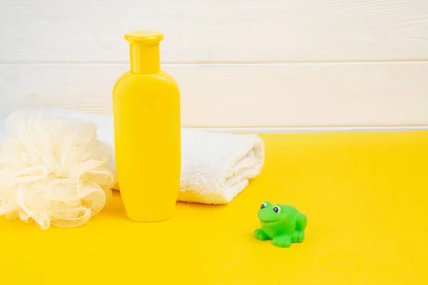 Spa ve banyo konsepti. Bebek banyosu seti ve sarı arka planda plastik kurbağa..