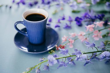 Yazlık konu fotoğrafçılığı. Bir fincan kahve ve mor çiçekler.