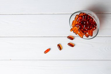 Kırmızı haplar cam kaseye saçılmış.