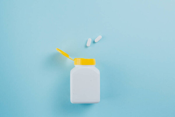 Таблетки разбросаны по бутылке на голубом фоне
