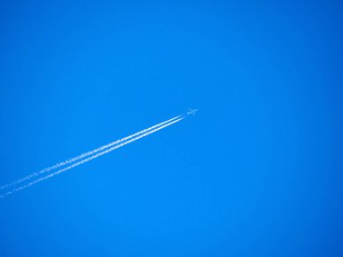 Uçak motorunda egzoz gazı izleri var. Beyaz çizgiler ve parlak mavi gökyüzünde bir uçak. Beyaz buğulanmış modern jet uçağı. Seyahat konsepti. Güzel arkaplan veya duvar kağıdı.