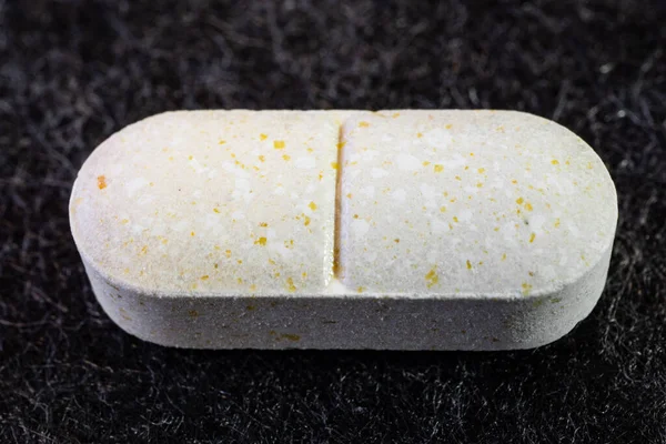 Beyaz bitkisel opioid haplarına yakın çekim. Gri mikrofiber yüzeyde beyaz oval tablet görüntüsü. Görünür en küçük yapı elementleri. Kopya alanı ile tıp konsepti teması arkaplanı.