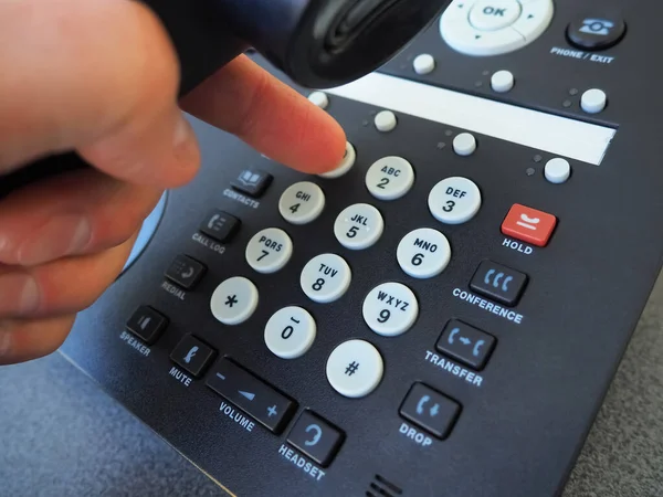 Siyah bir sabit telefondan arama yapmak için bir telefon numarasını çevirirken, bir erkeğin telefon ahizesini tutarken yakın plan görüntüsü. Küresel iletişim kavramı, iş desteği ve müşteri bakımı.