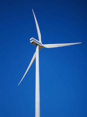 Boş bir alanda rüzgar jeneratörü. Güneşli bir günde yeşil enerji. Bulutlu mavi gökyüzü. Ekoloji ve Enerji Koruma Konsepti.