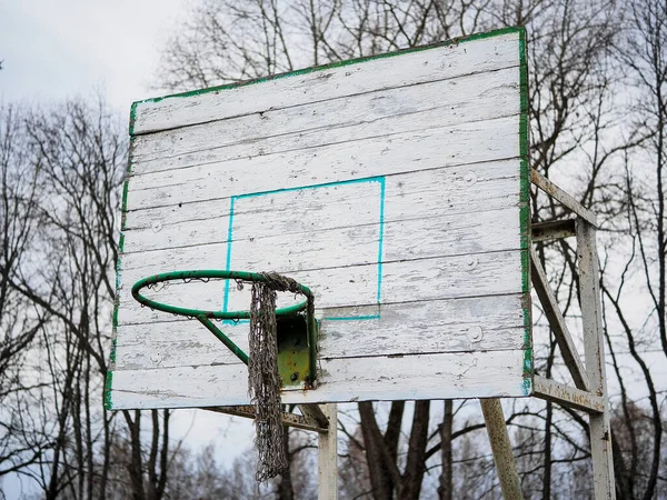 Eski, kırık, zarar görmüş, arka tahtası çizilmiş ve örgüsü yırtılmış basketbol potasına yakın çekim. Sağ wiev.