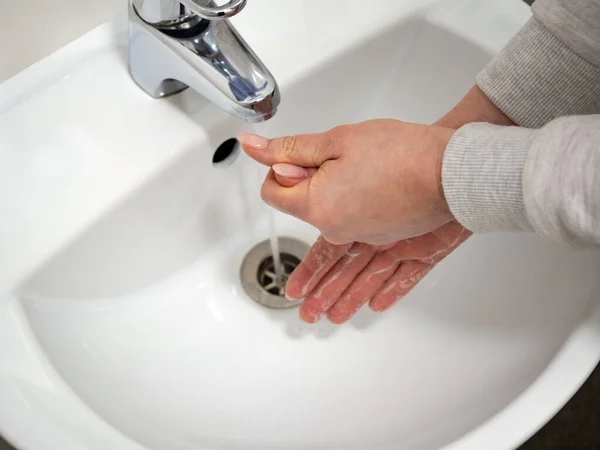 Koronavirüs mikroplarının salgın hastalık yaymasını önlemek ve tamamen dezenfekte etmek için musluğun altında sıvı sabunla düzgün bir şekilde el yıkama. Hijyen ve sağlık temizliği kavramı.