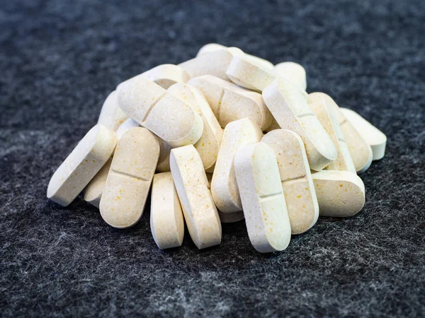 Beyaz bitkisel opioid haplarına yakın çekim. Gri mikrofiber yüzeyde beyaz oval tabletler yığını. Fotokopi alanı ile tıp suçu konsepti teması.