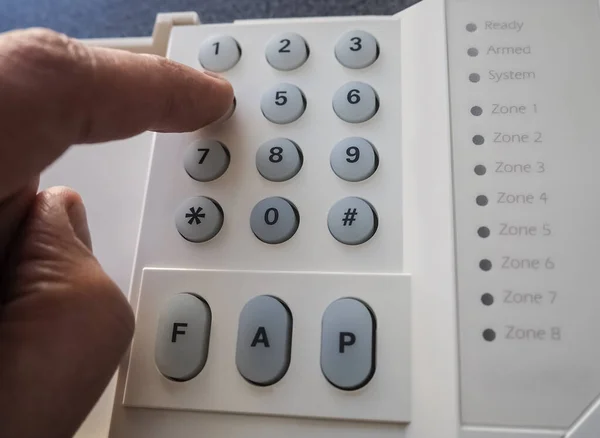 Close-up of security alarm keypad with person arming the system concept for crime prevention. High-quality macro photography.