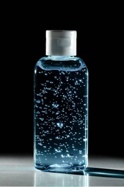 Bottle of instant antiseptic hand sanitizer transparent gel isolated on black background, no label.  Antibacterial, hydro alcoholic gel, ethyl alcohol. Mini travel pocket small size, 8 fl oz, 50, 60 ml. COVID-19 Pandemic Coronavirus, cold, flu hygien clipart