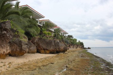 Sandy plaj, tropikal ağaçlar ve t kırmızı kiremit ile beyaz evler
