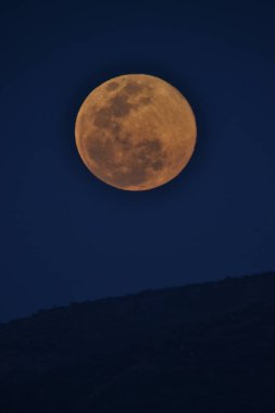 Dolunay bir dağdan yükseliyor.