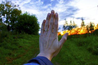 Yüzükle elini kapat. Orman ve günbatımı arka planda