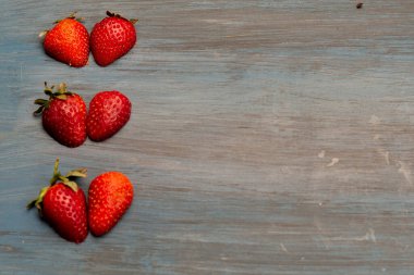 Çilekler kalp şeklinde, masa mavisi üzerinde, beyaz için kavramsal.
