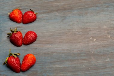 Çilekler kalp şeklinde, masa mavisi üzerinde, beyaz için kavramsal.