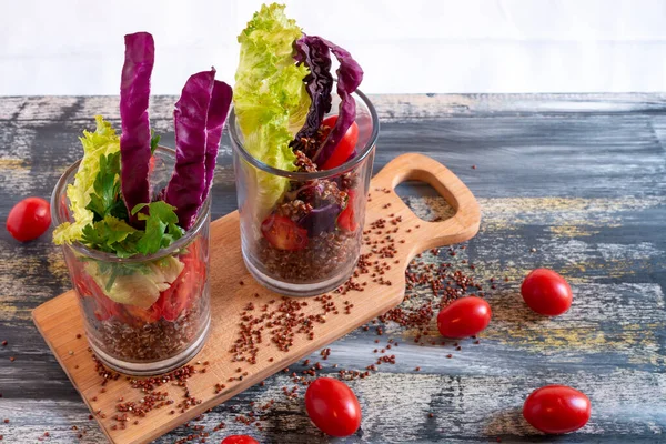 Red quinoa salad with tomato on a rustic table. Superfood and healthy eating concept.