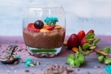 Çikolatalı puding, chia, çikolata ve çilek mavi bir masada.