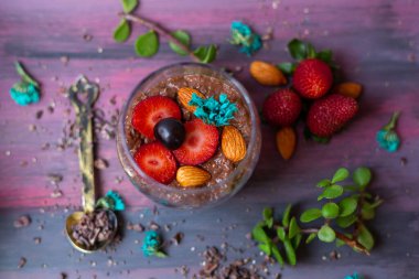 Çikolatalı puding, chia, çikolata ve çilek mavi bir masada.