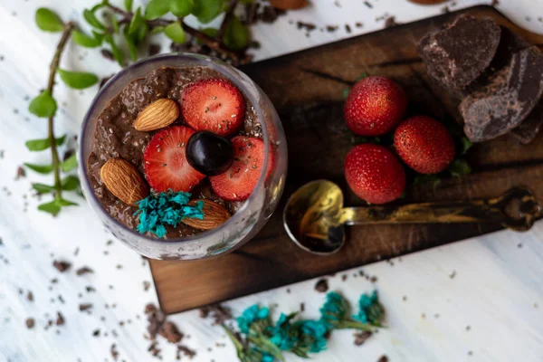Çikolatalı puding, chia, çikolata ve çilek mavi bir masada.