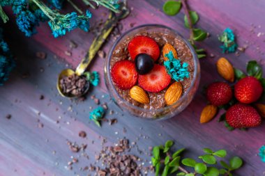 Çikolatalı puding, chia, çikolata ve çilek mavi bir masada.