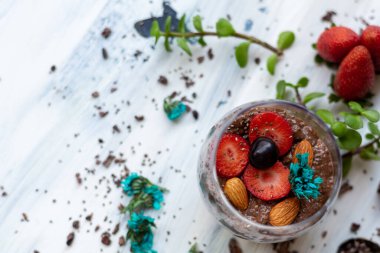 Çikolatalı puding, chia, çikolata ve çilek mavi bir masada.