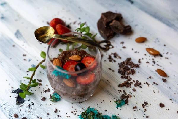 Chocolate pudding with chia, chocolate and strawberries on a blue table