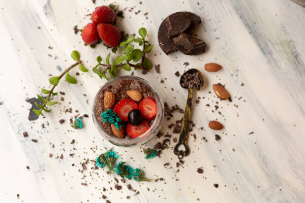 Шоколадный пудинг с чиа, шоколадом и клубникой на голубом столе
