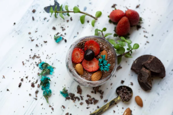 Chocolate pudding with chia, chocolate and strawberries on a blue table