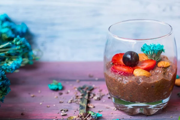 Chocolate pudding with chia, chocolate and strawberries on a blue table