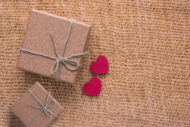 Kahverengi hediye kutusu ve kumaş arka plan üzerinde iki kırmızı kalp