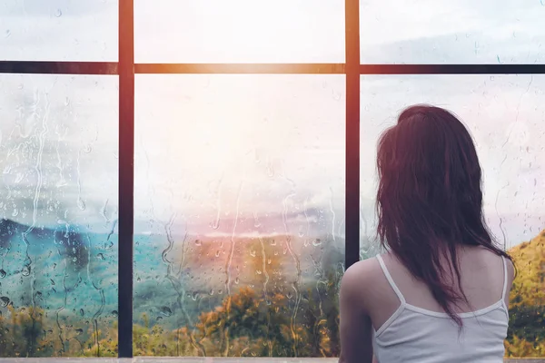 Dışarıda yağmur ile pencere önünde oturan yalnız kadın