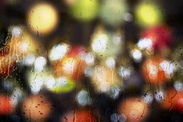 Raindrops on glass window with colorful of night light outside. — Stock Photo, Image