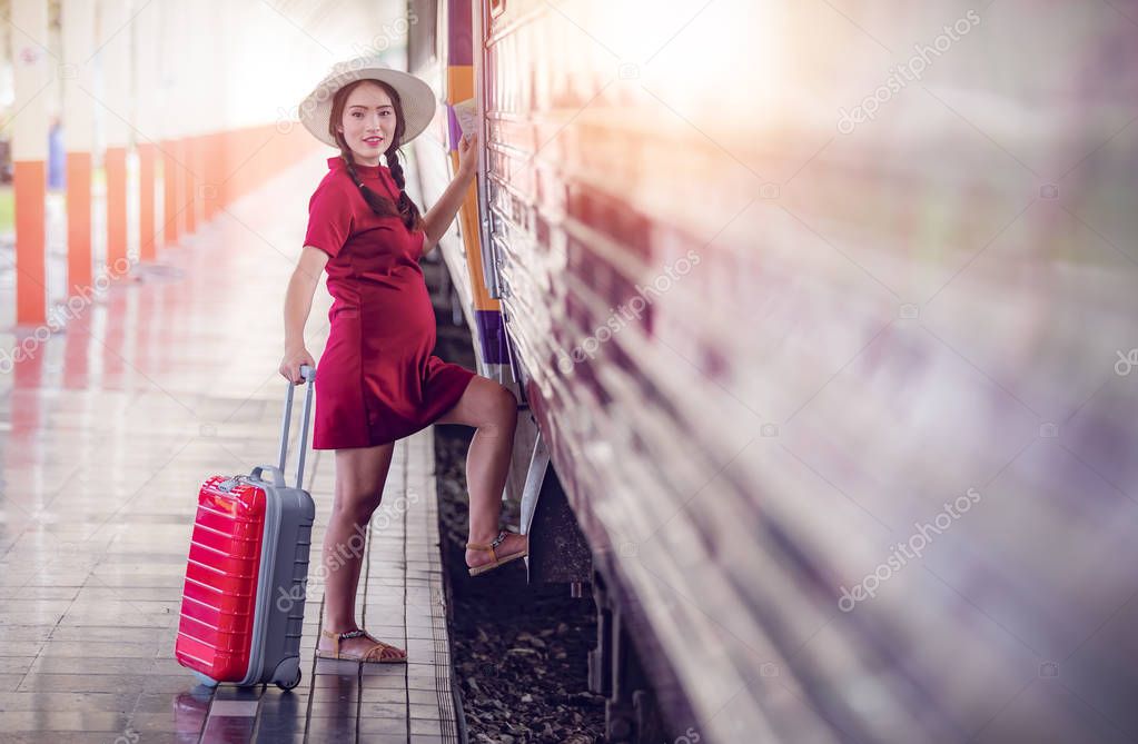 asian pregnant woman in red dress are stepping up the train