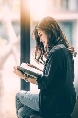 Güzel kadın sabah sunlig penceresiyle tarafından bir kitap okuma