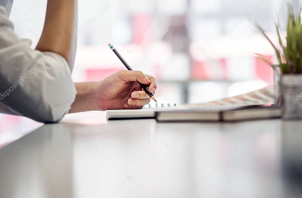 Close up short of businessman hand holding pencil while sitting 