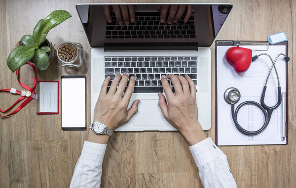 Doctor working at office desk and using a laptop computer