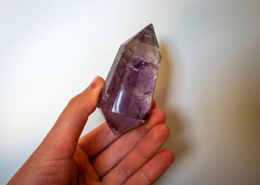 feale hand holding a purple crystal point wand that could be amethyst or ametrine clipart