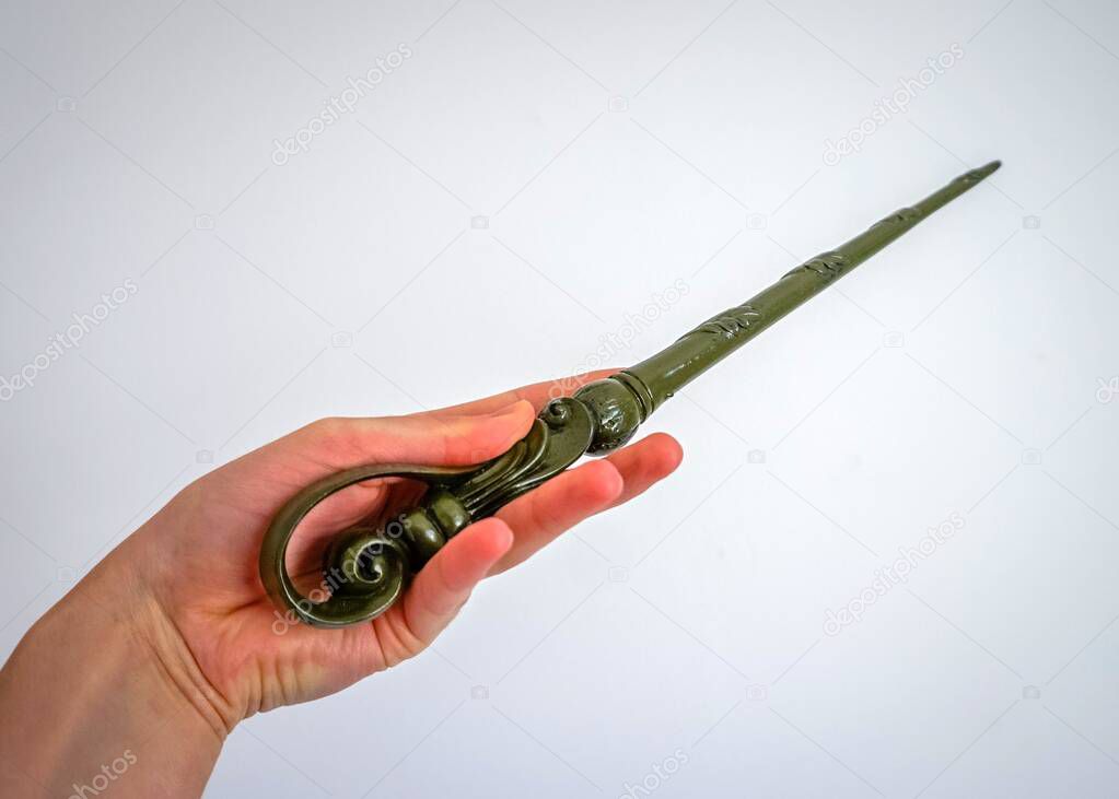 A female hand holding a green magic wand on a white background. Girl performing magic and hermione granger cosplay