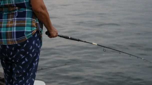 渔夫和小孩坐在海边的栏杆上 用钓竿捕鱼 — 图库视频影像