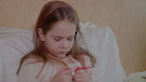 Symptome von Fieber und Coronavirus, ein Mädchen misst die Körpertemperatur. Aufgebrachtes Mädchen blickt auf ein digitales Thermometer in der Hand, das Konzept der Erkältung und Grippe — Stockvideo