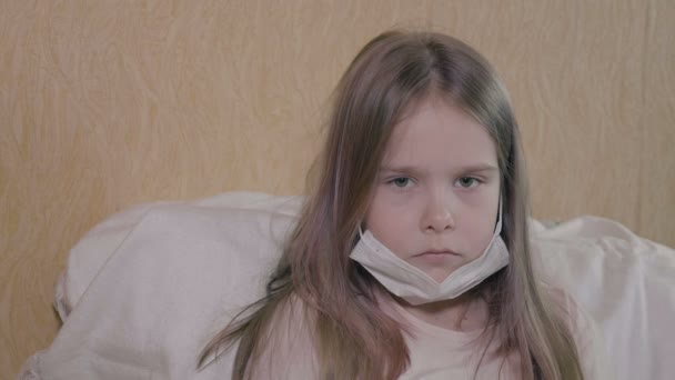 The girl has a severe headache and fever. The girl has ncov-19 coronavirus. The girl wears a medical mask, self-isolation. — Stock Video