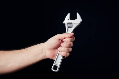 Siyah arka planda bir ingiliz anahtarını tutan