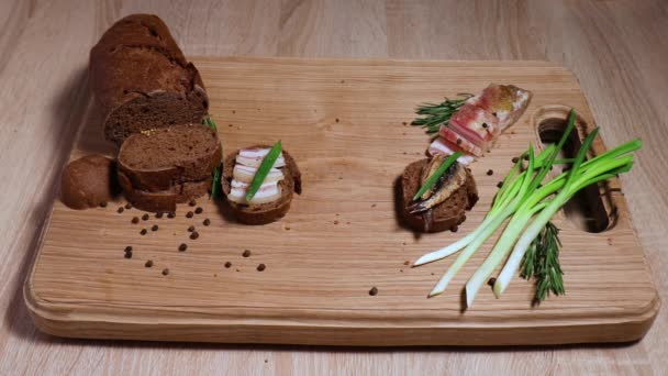 Three sandwiches in the Russian style: with lard, with fish, with pickles and green onions, and three glasses with a traditional alcoholic drink. Still life on a white oak board. — Stock Footage Three Sandwiches Russian Style Lard Fish Pickles Green Onions Three Video Clip