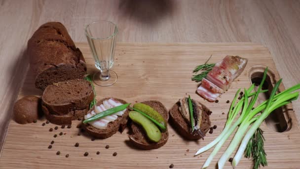 The man's hand puts three vintage glasses on the table and pours a traditional Siberian alcoholic drink. Three sandwiches in the Russian style: with lard, with fish, with pickles and green onions. — Stock Footage Man Hand Puts Three Vintage Glasses Table Pours Traditional Siberian Stock Video