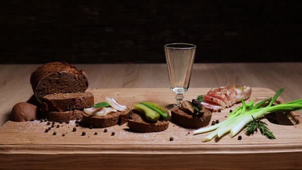 The man's hand puts three vintage glasses on the table and pours a traditional Siberian alcoholic drink. Three sandwiches in the Russian style: with lard, with fish, with pickles and green onions. — Stock Footage Man Hand Puts Three Vintage Glasses Table Pours Traditional Siberian Royalty Free Stock Video