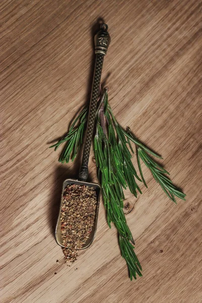 A beautiful vintage scoop with fragrant spices, on green sprigs of rosemary, on a white oak kitchen board. Recipe book with meat dishes and salads. Vintage still life in warm colors.