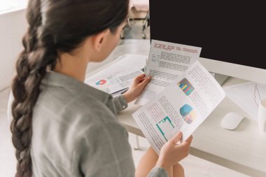 Serbest çalışanın evde çalışırken grafik ve grafiklere baktığı yüksek açılı görünüm