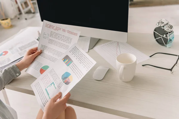 Serbest çalışanın kahve fincanı ve tıbbi maskeye sarılı çalar saatin yanındaki grafiklere ve çizelgelere baktığı görüntüler.