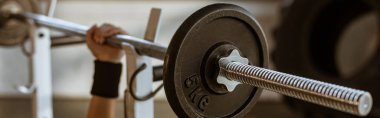 Spor salonunda halterli bir kadının yatay görüntüsü.