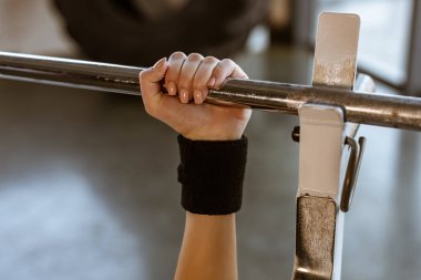 Spor salonundaki halteri tutan kadın görüntüsü.